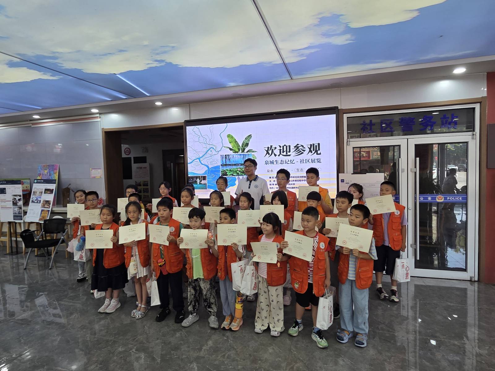 Young docents in orange vests holding certificates at the Spring City Eco-Memory community exhibition