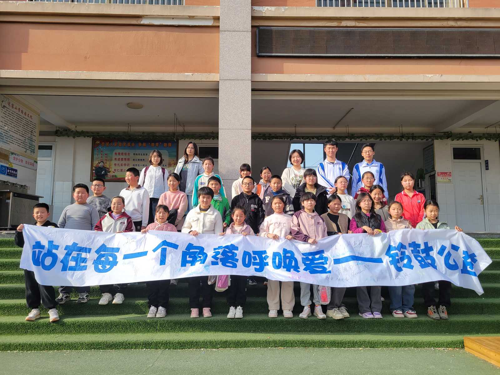 Group photo of volunteer tutors and pupils holding the banner 'Calling for Love in Every Corner'