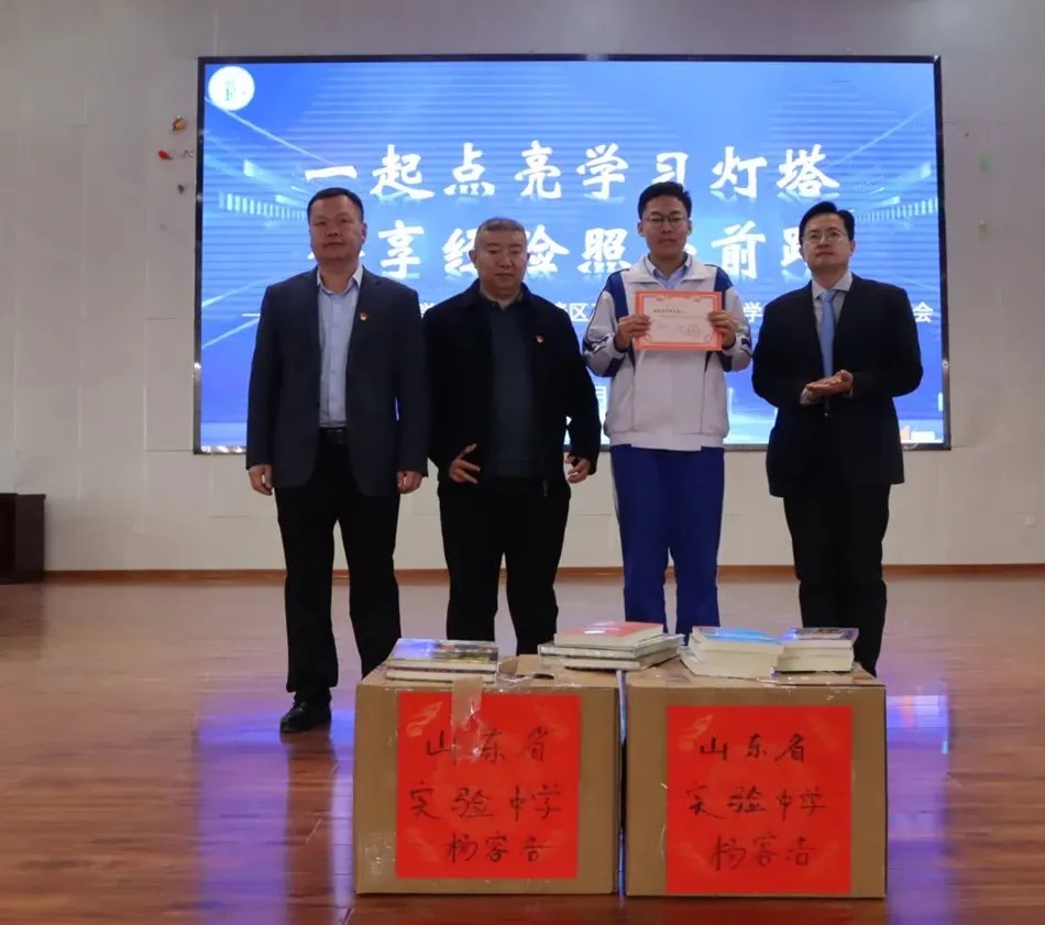 Ronghao Yang holding a certificate beside two cartons marked with his name and school at the “Heart Growth” ceremony